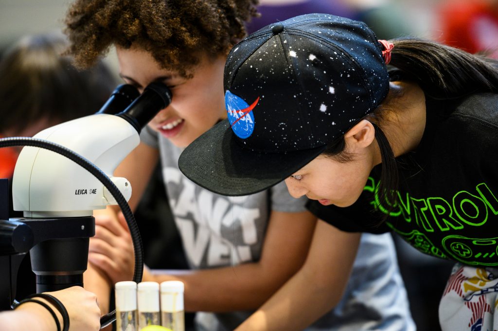Friends Fury Townsel, at left, 10, and Rio Heidenreich, 11, use a microscope to look at various organisms during a Science Expeditions activity in the Health Science Learning Center at the University of Wisconsin-Madison on April 7, 2019. This was the third day of Science Expeditions, a three-day-long education-outreach event involving multiple disciplines and held at a number of host locations throughout campus. (Photo by Jeff Miller / UW-Madison)
