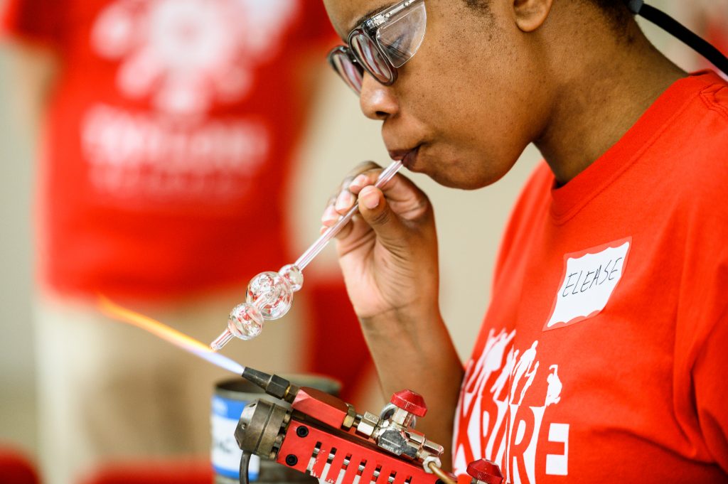Graduate student Elease McLaurin shapes a sample of scientific glassware during a glassblowing demonstration at Science Expeditions in the Discovery Building at the University of Wisconsin-Madison on April 6, 2019. This was the second day of Science Expeditions, a three-day-long education-outreach event involving multiple disciplines and held at a number of host locations throughout campus. (Photo by Jeff Miller / UW-Madison)
